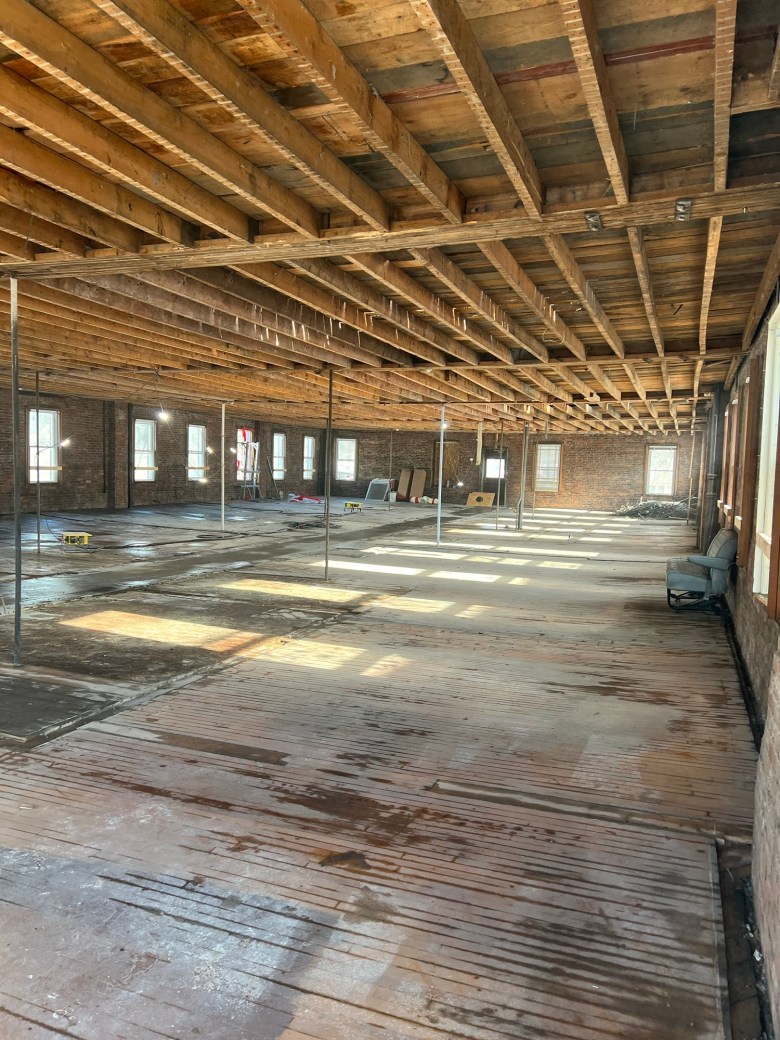 The inside of a building with wooden floors and beams.